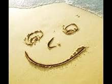 Smiley happy face drawn on beach sand
