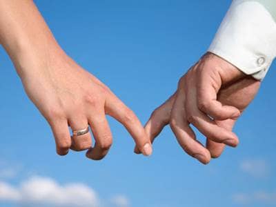 Couple's fingers touching against a blue sky