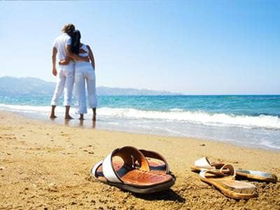 Sandals and couple on sandy beach
