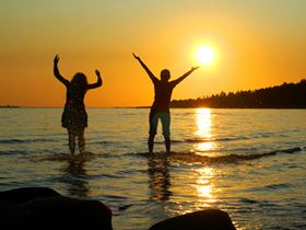 Two people by beach praising the sun