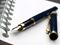 An uncapped ink fountain pen on a spiral-bound notebook.