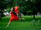 Woman leaping in red dress with red heart balloons