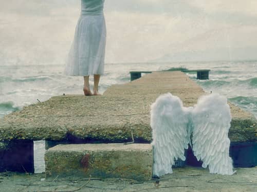 Woman walking on pier with white angel wings