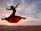 Woman dancing in desert against sunset