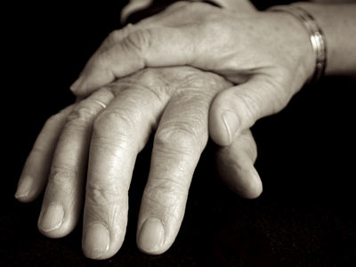 Black and white hand comforting an elderly person's hand