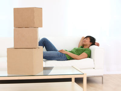 Woman resting on a couch, stacked boxes on a table.
