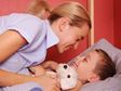 Mother tucking son into bed