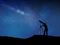 Man looking through telescope under a starry night sky