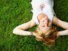A similing woman lying on a green field
