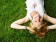 A similing woman lying on a green field