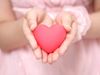 Little girl in a pink dress holding a pink heart