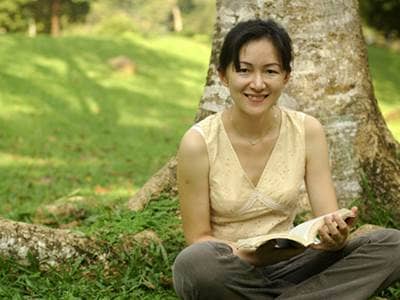 Asian woman reading under a tree.