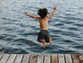 Boy Jumping into water from dock
