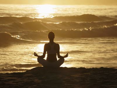 Silhouette of woman meditating on beach