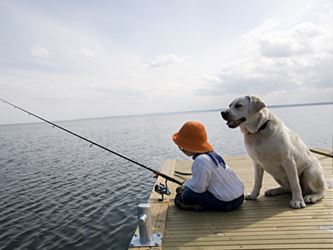 Little girl fishing, with a yellow labrador retriever at her side