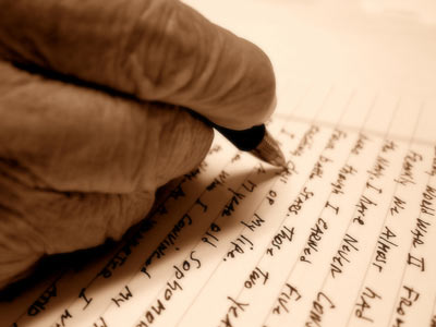 An elderly hand correcting a letter with a pen