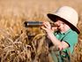 Little boy in a safari hat looking through a telescope