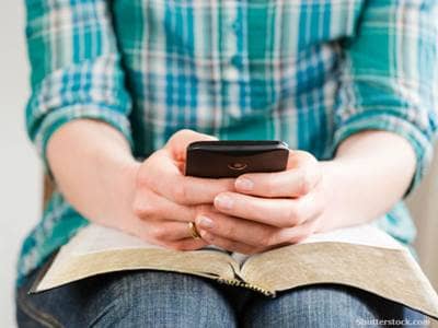 Person on smartphone over Bible