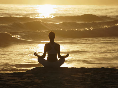 Silhouette of woman meditating on beach